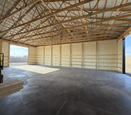 Pole barn walls insulated with spray foam under an open wooden truss roof in Pennsylvania